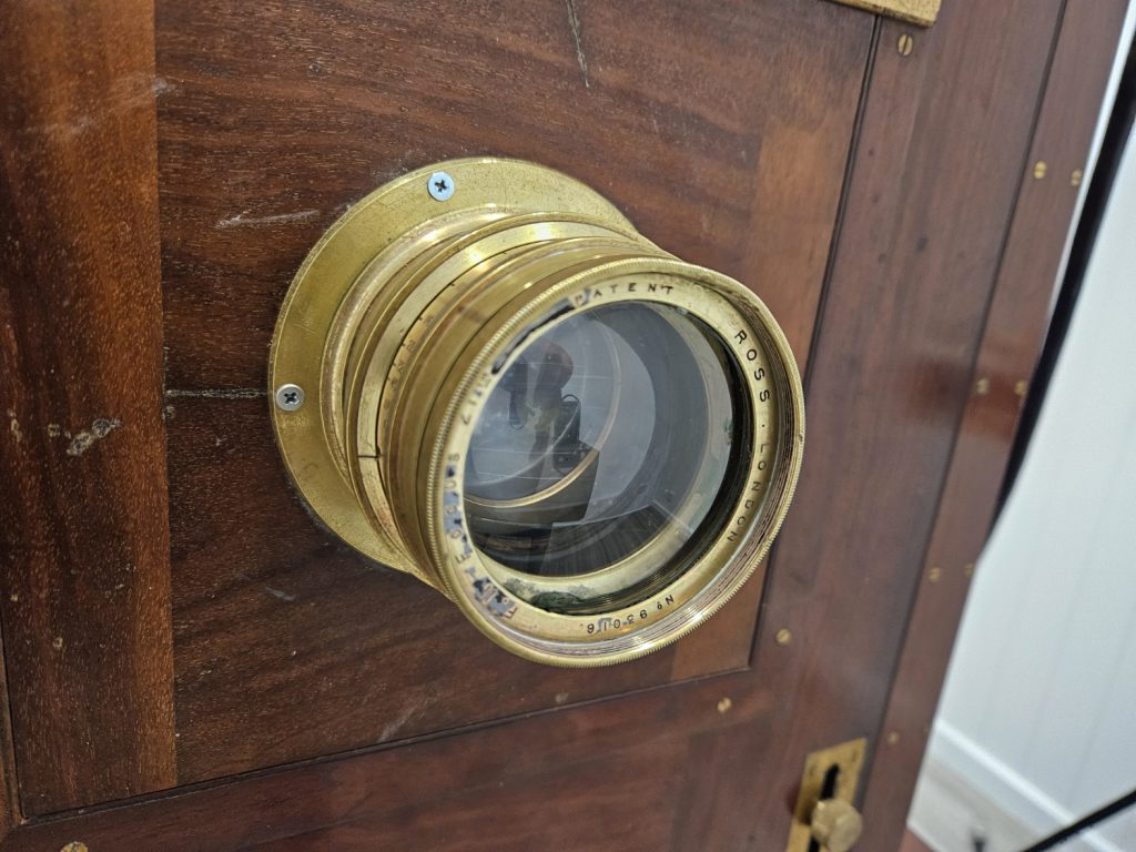 Brass Ross Combination lens mounted on a wooden camera front after restoration
