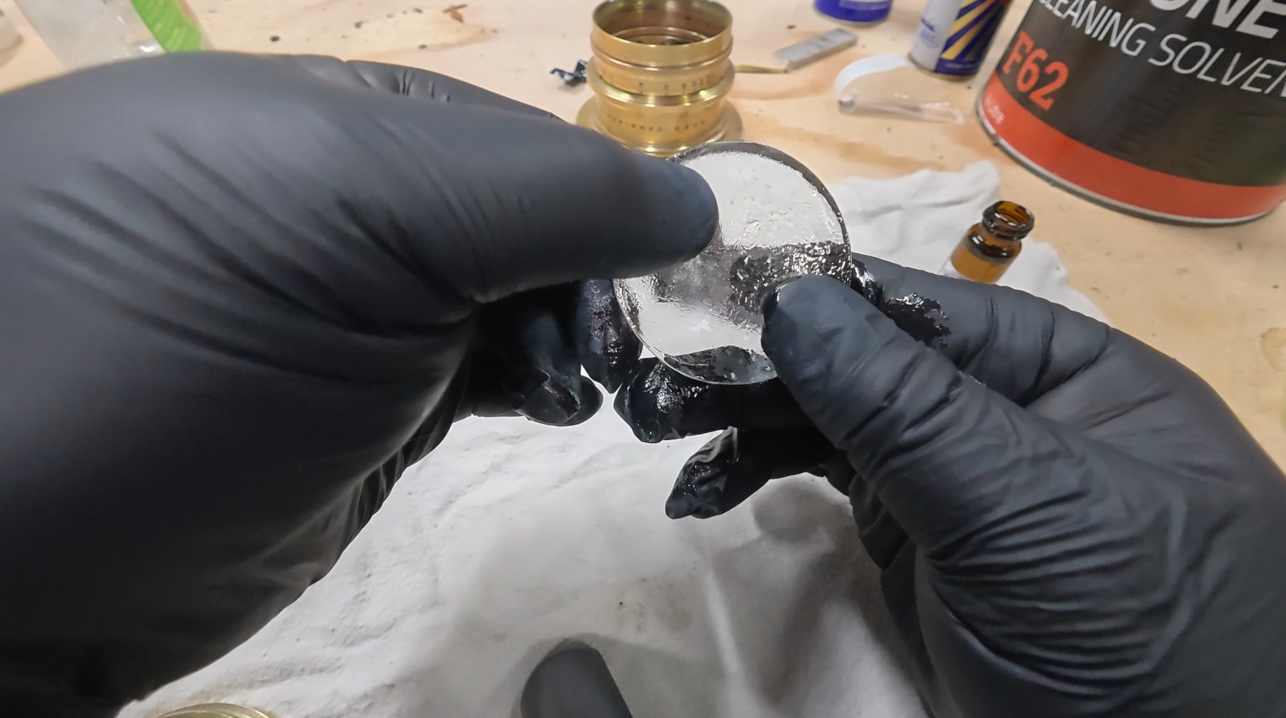 Gloved hands working on a glass lens element during the Ross restoration