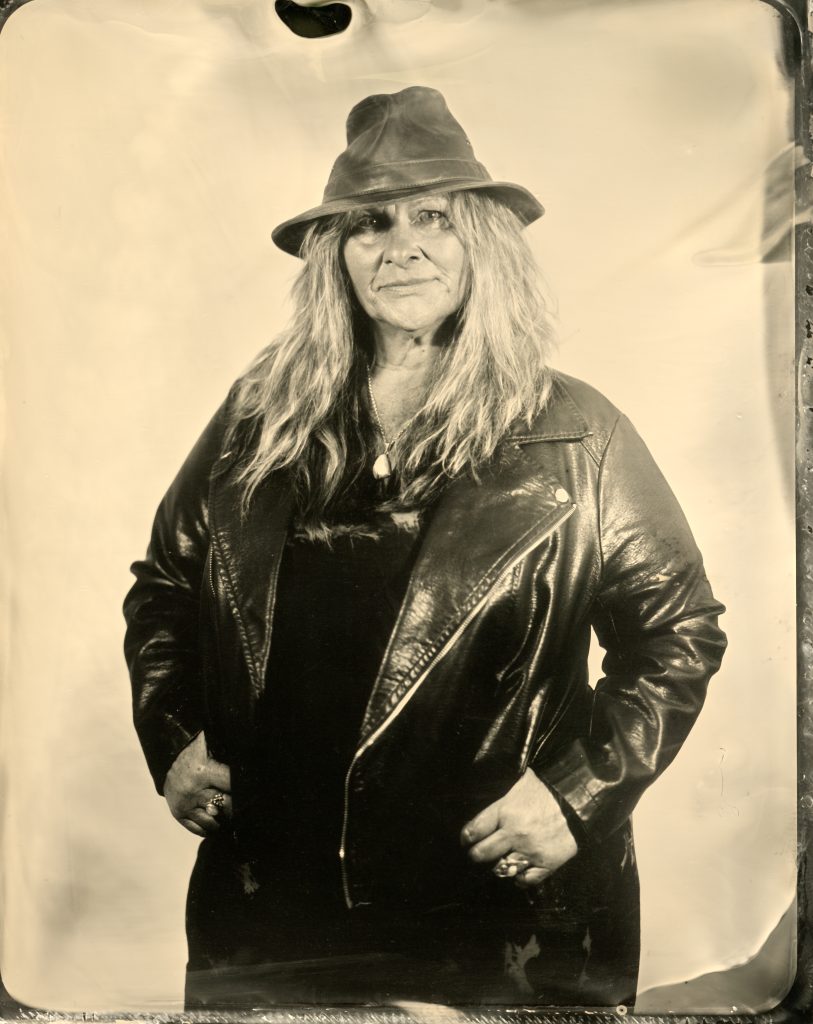 Full-length wetplate portrait of a woman wearing a hat and leather jacket