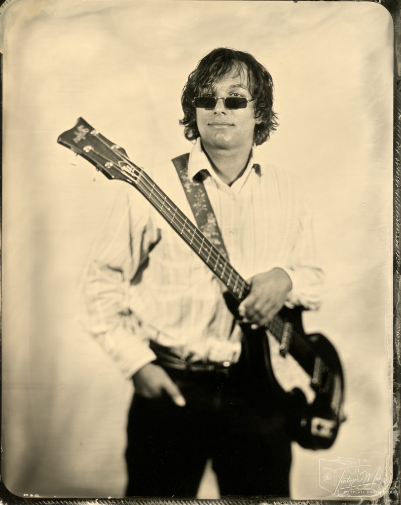 Wetplate portrait of a musician wearing sunglasses and holding a guitar.