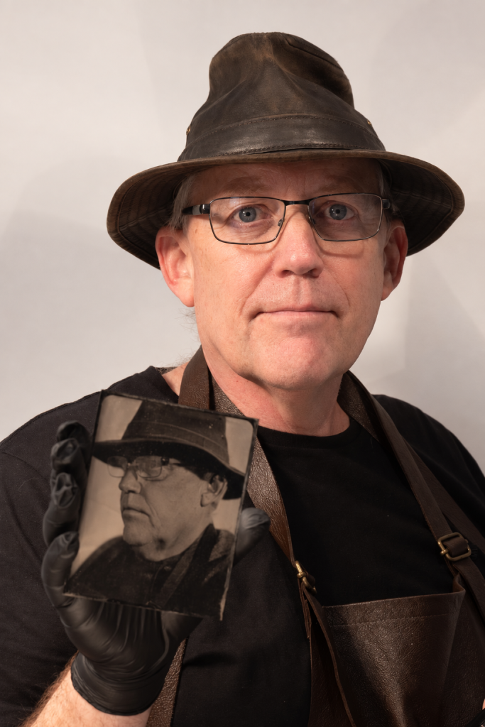 Scott Longden, Tintypeman, holding a handmade tintype portrait.